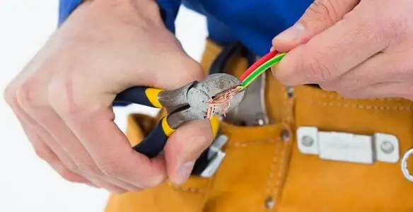 licensed electrician securing electrical wiring with professional tools during service work in Orange, CA