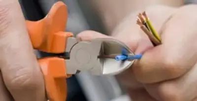 licensed electrician performing precise wire cutting and preparation during electrical service in Orange, CA