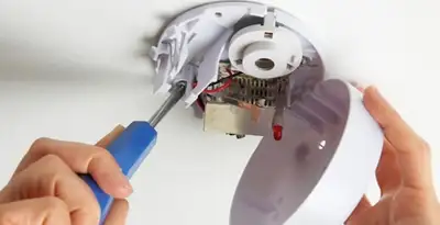 Certified technician wiring smoke detector during installation in Orange, CA